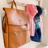 A Scarlett - Caramel backpack hanging on a clothes rack.