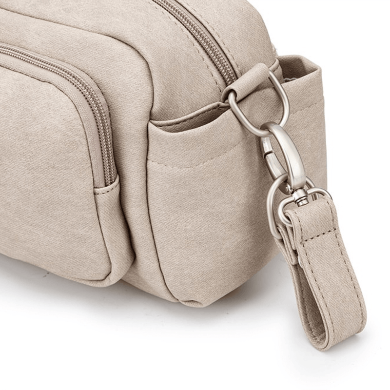 Beige canvas Pram Caddy with adjustable shoulder strap, featuring a detailed view of its zipper and metal clasp on a white background by Mother and Baby.