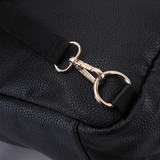 A close up of a Lily - Black leather bag with a gold buckle by Mother and Baby.