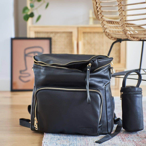 A Mother and Baby - Ava Black backpack with a gold zipper on the floor.