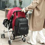 A woman pushing a stroller with the Olivia - Black backpack by Mother and Baby.