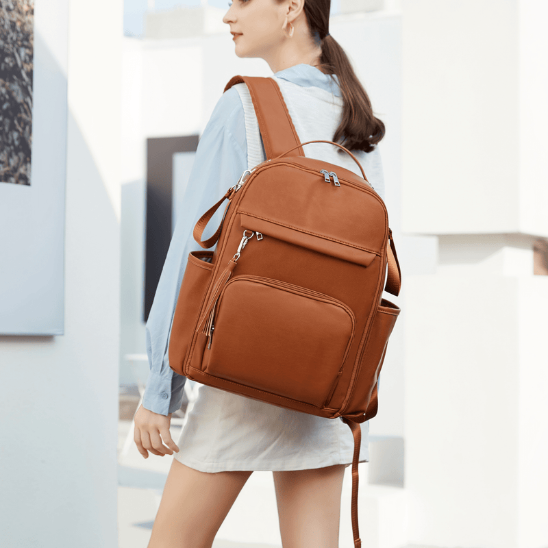 A woman wearing an Olivia - Caramel backpack from Mother and Baby.