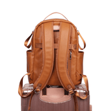 An Olivia - Caramel leather backpack on top of a suitcase. (Brand: Mother and Baby)