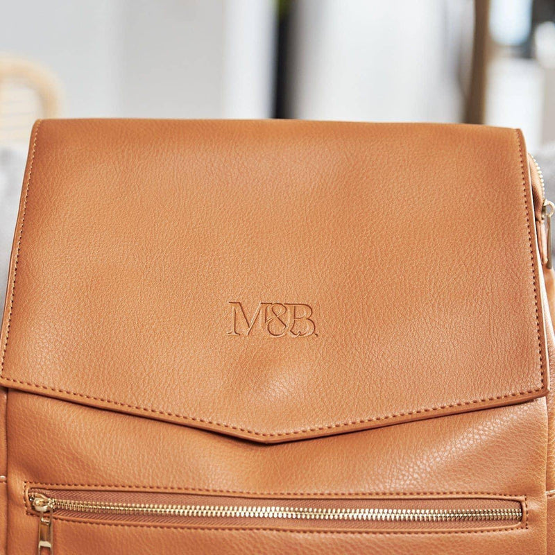 A Scarlett - Caramel backpack with a monogram on it made by Mother and Baby.