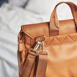 A Scarlett - Caramel leather bag on a bed by Mother and Baby.