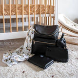 A Sophia - Black diaper bag and other items on the floor of a baby's room.
