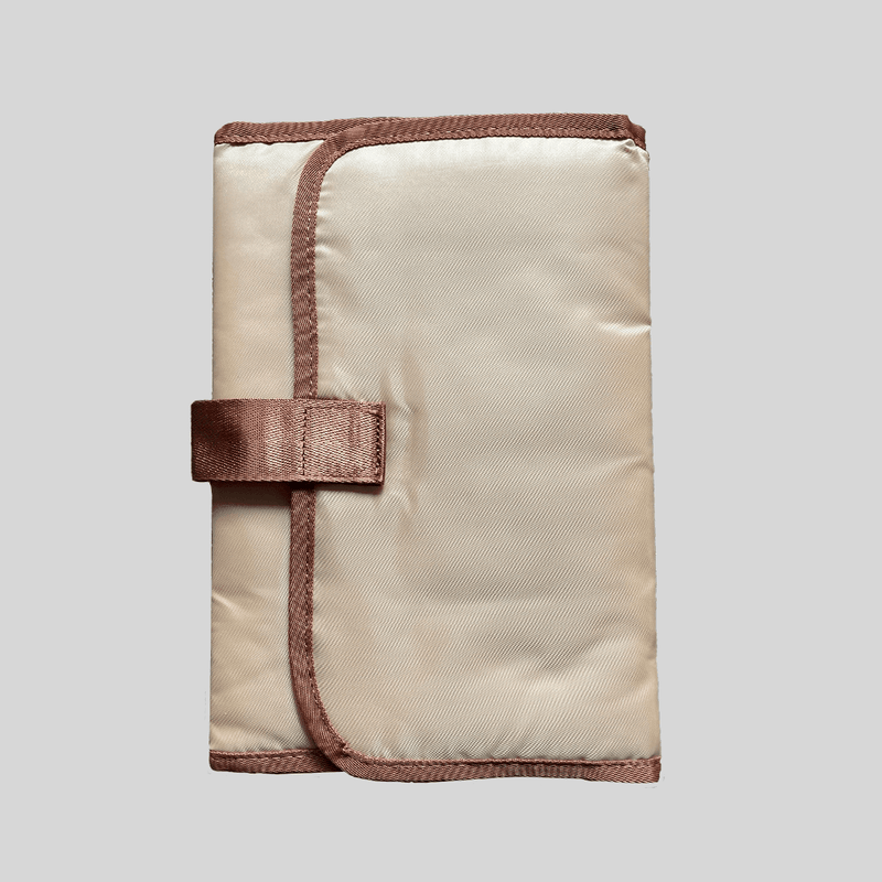A Portable Changing Mat - Caramel with a brown strap by Mother and Baby.