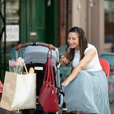A woman pushing a stroller with Mother and Baby Luxe Stroller Strap.