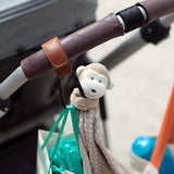 A Luxe Stroller Strap with a monkey hanging from the handle made by Mother and Baby.