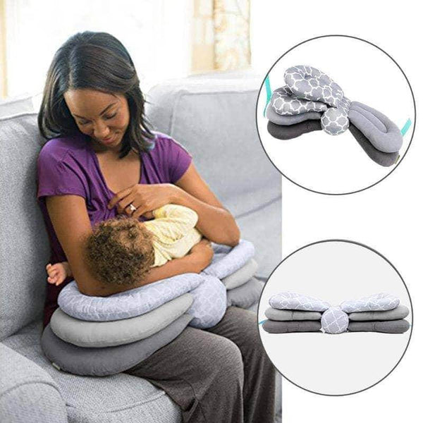 A woman is using the Mother and Baby Adjustable Breast Feeding Pillow to breastfeed her baby on a couch.